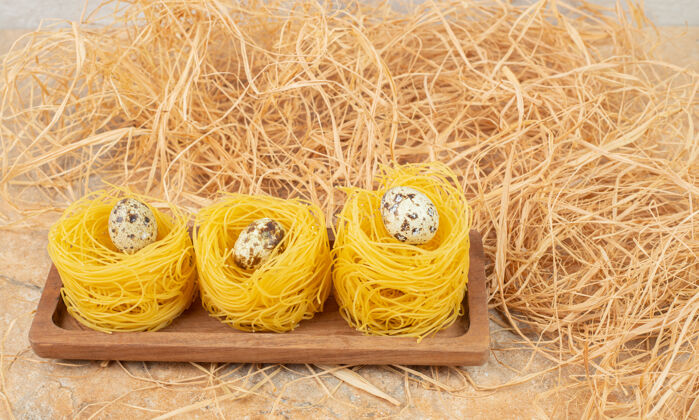美味鹌鹑蛋放在意大利面上 卡佩里尼放在稻草旁边的木板上 放在大理石上生的板营养