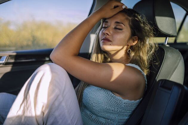 汽车一个美丽的年轻白人女性在一个领域的汽车前排座位摆姿势的水平镜头太阳人背景