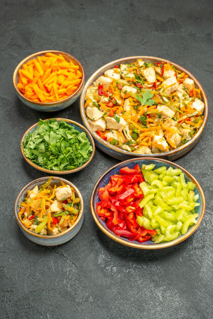 午餐前视图鸡肉沙拉和蔬菜在深灰色的餐桌上饮食健康沙拉蔬菜鸡肉沙拉晚餐
