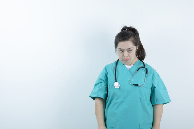 医生年轻的女护士用听诊器对着白墙摆姿势女人人悲伤