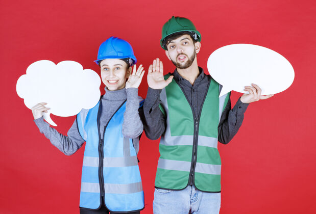 工人男女工程师戴着头盔 手持云彩和椭圆形信息板 试图阻止什么东西员工成人人