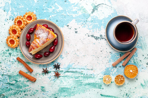 切片俯瞰美味的蛋糕片与一杯茶和饼干上的蓝墙蛋糕烤派饼干甜生的颜色咖啡