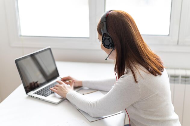 耳机工作中的女人正在笔记本电脑上进行视频通话办公桌女士办公室