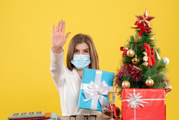 礼物正面图：戴着无菌口罩的女医生带着礼物圣诞人物流行病