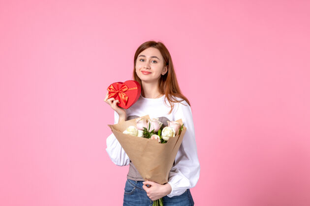 玫瑰正面图：带鲜花的年轻女性 在粉色背景上作为妇女节礼物赠送玫瑰横三月女性约会女性爱感官平等礼物年轻女性花束