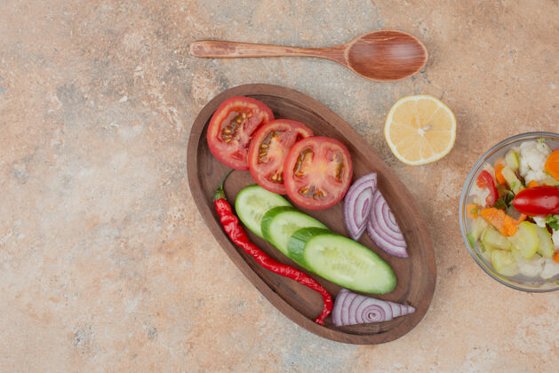 玻璃杯美味的蔬菜放在玻璃盘上 番茄 黄瓜和洋葱的木板放在大理石上汤匙食物柠檬