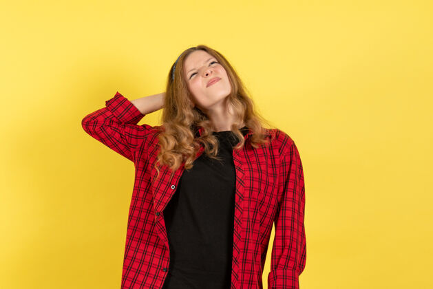 肖像正面图身着红色格子衫的年轻女性站在黄色背景上思考着一个模特儿人类女孩衬衫人类站