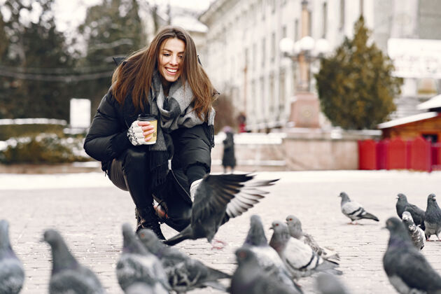 休闲站在街上被鸽子包围的女人霜冻成人快乐