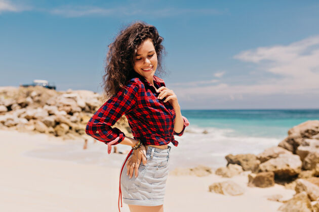人晒黑的快乐女人穿着格子衬衫和牛仔短裤在岛上放松度假旅游快乐