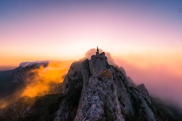 女性日落时 一只手举在山顶上的雌性鸟瞰镜头自然场景全景