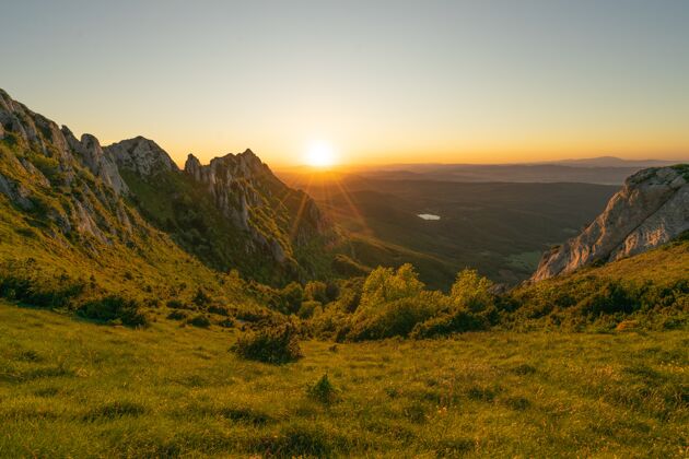 黎明在美丽的日落时刻 一座绿色岩石小山的迷人镜头黄昏海草地