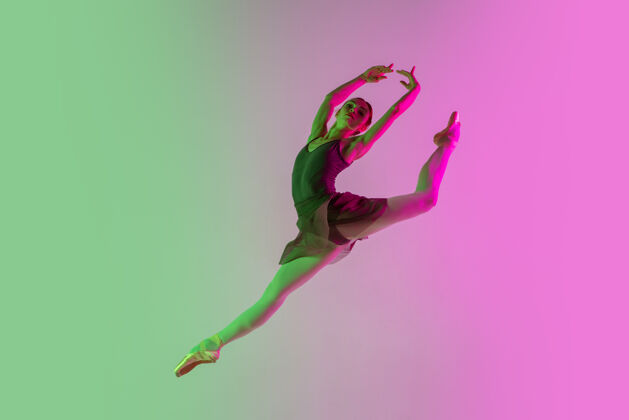 动作轻年轻而优雅的芭蕾舞演员在霓虹灯下被隔离在渐变的粉绿色墙壁上艺术 动作 动作 灵活性 灵感概念灵活的芭蕾舞演员 失重跳跃舞蹈渐变灵活