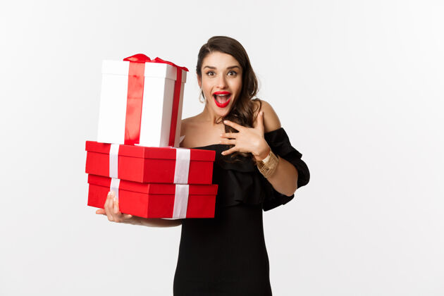 时尚庆祝和圣诞假期的概念兴奋和快乐的女人收到礼物 拿着圣诞礼物和喜悦 站在白色背景的黑色礼服礼品时尚魅力