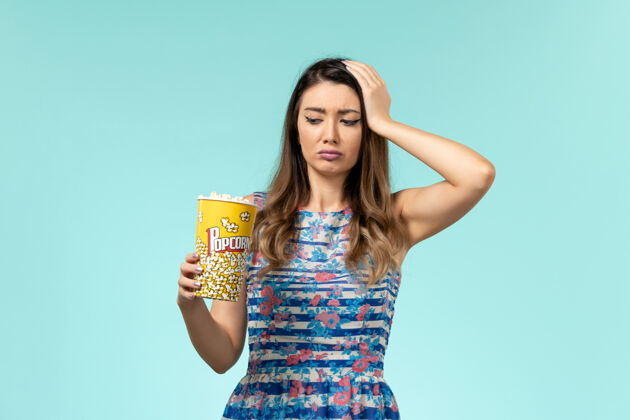 电影正面图年轻女性拿着爆米花包在蓝色的表面上吃漂亮电影剧院