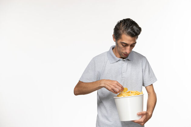 孤独正面图：年轻男性手提篮 白色表面上放着薯片抱着电影篮子