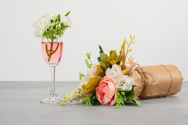 玫瑰一束鲜花和一杯玫瑰红酒在灰色的表面上婚礼鲜花五颜六色