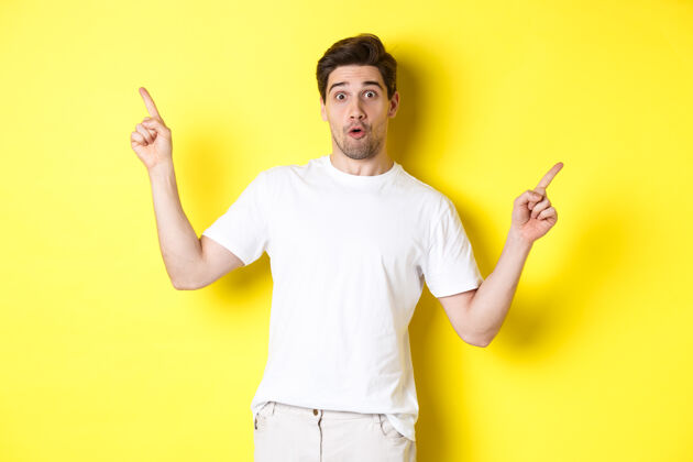 秀帅哥横着手指 展示两个宣传片 站在黄色背景上站男人自信