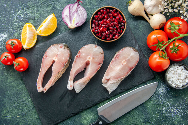 利器顶视图新鲜鱼片与红色西红柿在黑暗的表面海鲜海洋肉类海餐水辣椒沙拉膳食沙拉海洋