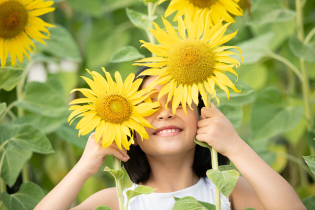 享受快乐的亚洲小女孩在阳光下 在盛开的向日葵中嬉戏花活跃快乐