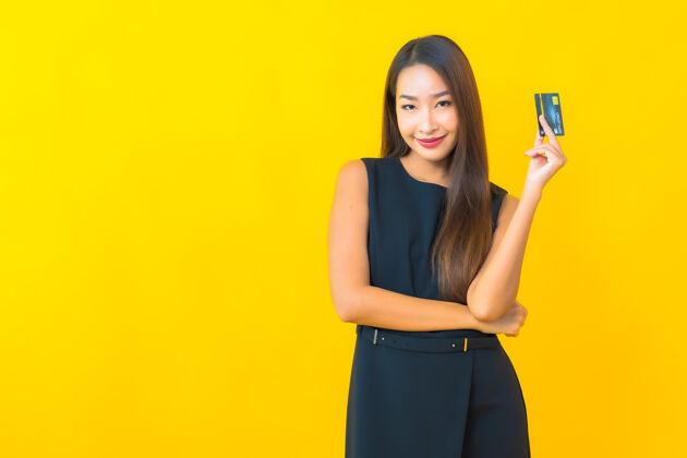 银行在黄色背景上用信用卡描绘美丽的年轻亚洲女商人金融在线电脑