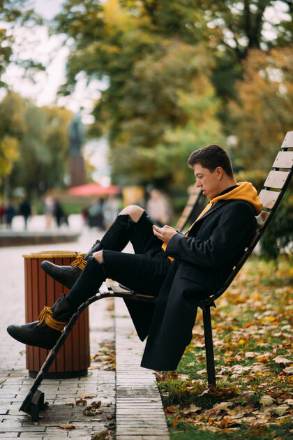 黄色坐在公园长椅上听音乐的年轻人时尚坐着都市