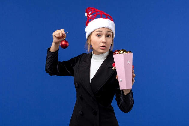 小姐前视图年轻女士拿着树玩具在蓝色的墙上情绪新年假期蓝色职业人前面