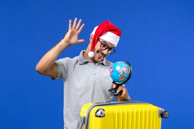 园艺工具正面图：年轻的男性背着黄色的包和地球仪在蓝色的飞机上度假旅行年轻男性男性工具