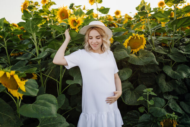 人一个穿着白裙子的金发女人在田里和向日葵在一起向日葵天空黑发