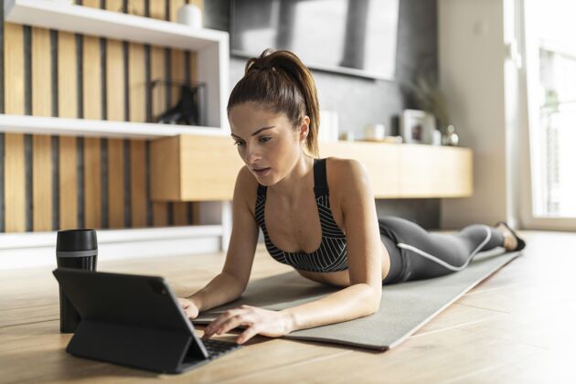 水平全速射击的女人在垫子上用平板电脑平板电脑运动锻炼