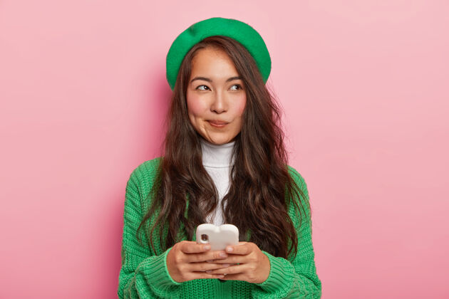 肖像漂亮的黑发日本女人用现代手机发短信 上网 有体贴的表情个人旁白女性