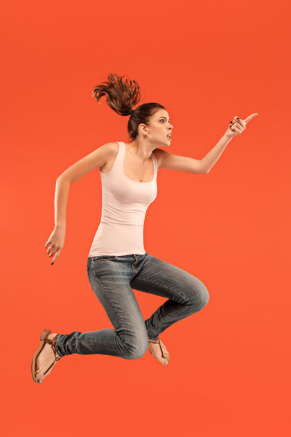 自信在移动的自由相当快乐的年轻女子跳跃和对橙色工作室的手势半空中拍摄情感移动自由