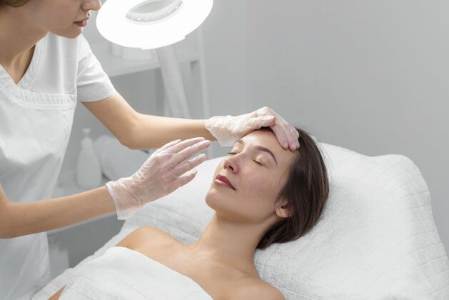 美容治疗美容师与女性客户在沙龙进行面部护理化妆品面部护理美容护理