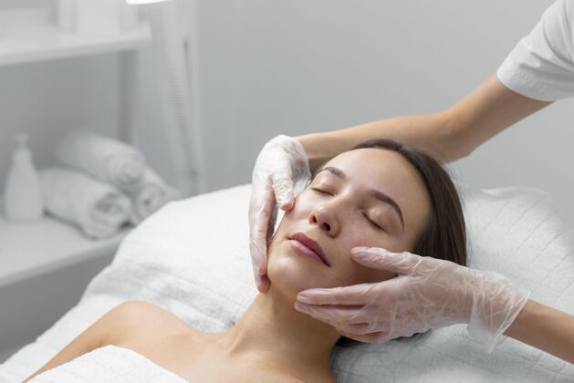 美容护理美容师与女性客户在沙龙进行面部护理美容院化妆品美容治疗