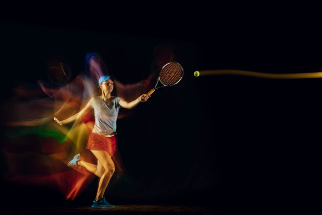 运动一位白人女子在黑色的墙壁上打网球 在混合和淡色的灯光下适合年轻的女性运动员在运动比赛中运动或行动运动的概念 运动 健康的生活方式球拍完整长度动作