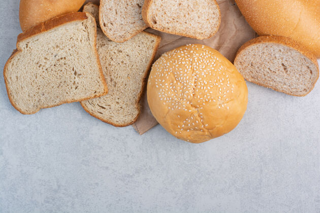 谷类面包片和芝麻包在纸上高品质的照片黑麦芝麻面包