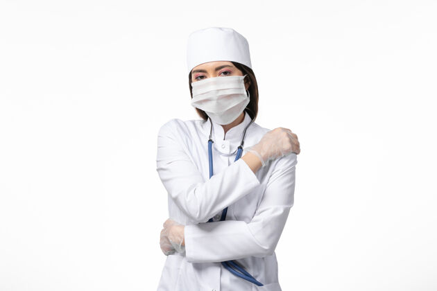 女性正面图女医生穿着白色医疗服 戴着口罩 因白墙上有冠状病毒 健康疾病大流行covid-西装医生疾病