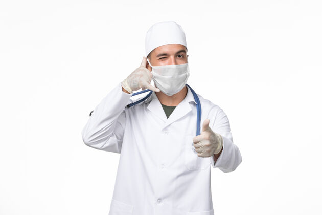 视图正面图：男医生穿着医疗服 戴着防毒面具 光壁上有防冠状病毒的冠状病毒病药物大流行病毒疾病大流行男性