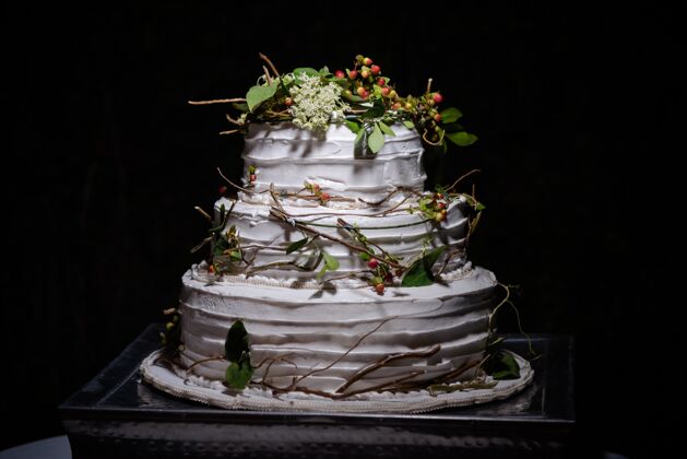 分支特写一个乡村婚礼蛋糕与绿叶 树枝和小圆形浆果花活动奶油