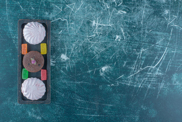 甜点在蓝色背景上的小托盘里放着一个果酱 饼干和一个巧克力蛋糕高质量的照片美味曲奇果酱
