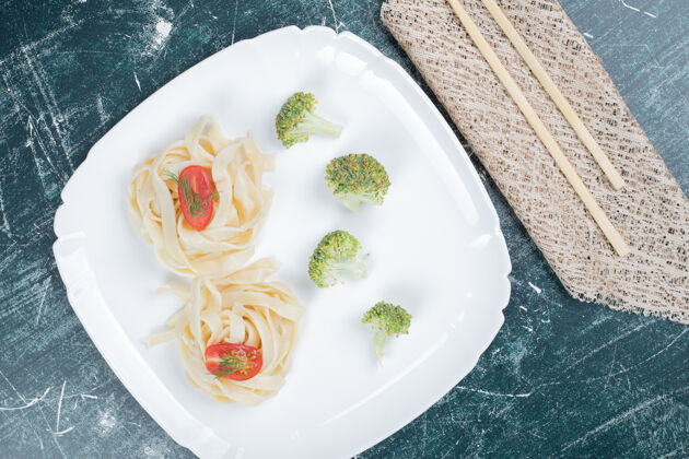 面食白盘子上煮意大利面配西兰花和番茄片高质量照片筷子Tagliatelle盘子