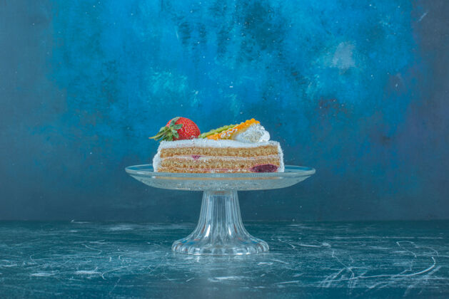 甜点水果蛋糕片放在蓝色背景的玻璃底座上高质量的照片顶部蛋糕草莓