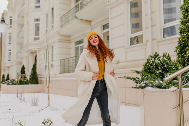冬天迷人的白大褂女孩在街上跳舞迷人的欧洲女模特在冬天微笑着摆姿势休闲外套红发