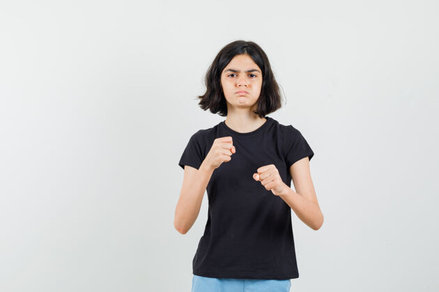 愤怒小女孩站在拳击姿势在黑色t恤 短裤和看起来愤怒 前视图漂亮休闲女性
