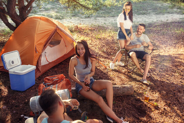 年轻聚会 男女在森林露营他们在绿草上放松度假 夏天 冒险 生活方式 野餐的概念朋友团体户外