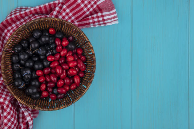 空间顶视图的水果 如山茱萸和树莓在篮子上的格子布蓝色背景与复制空间树莓蓝色食物