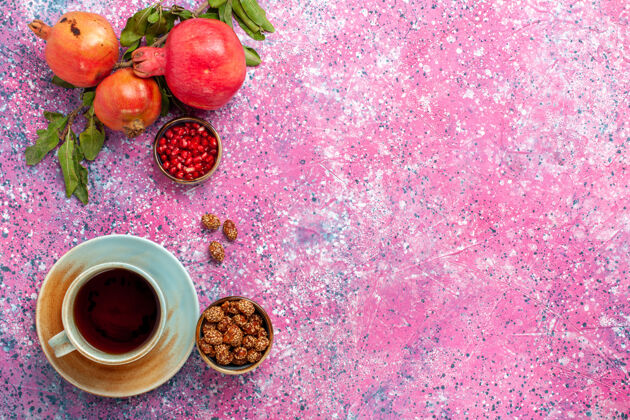 咖啡顶视图新鲜石榴与绿叶和一杯茶在粉红色的表面新鲜树生的