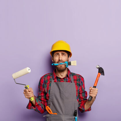 沮丧上门维修的男职工忙着房屋装修 手里拿着建筑设备刷子锤子人