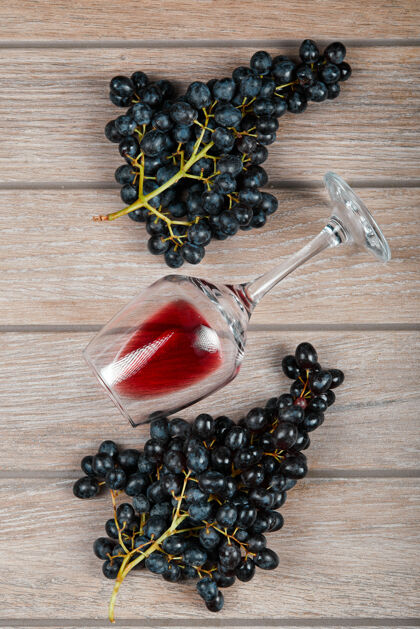 表面木桌上放着一束黑葡萄和一杯葡萄酒桌子新鲜木材