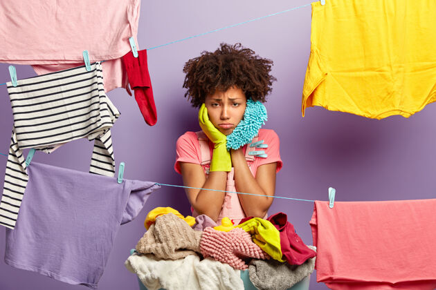 干心烦过度劳累的家庭主妇用衣夹把衣服挂在洗衣线上房子家庭主妇家务