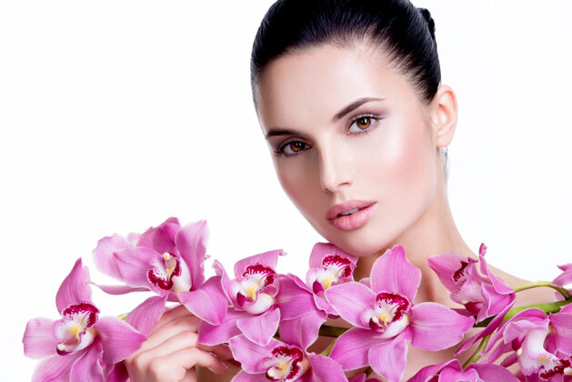 漂亮美丽的年轻漂亮的女人 拥有健康的皮肤和靠近脸部的花朵-隔离在白色上花水疗新鲜